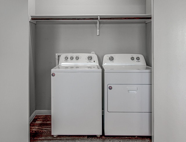 clothes washing area featuring washer and clothes dryer, laundry area, baseboards, and wood finished floors