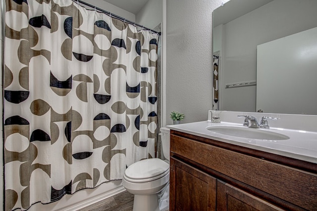 full bathroom with vanity, wood finished floors, shower / bath combo, toilet, and a textured wall