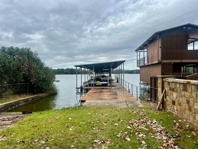 view of dock with a yard and a water view