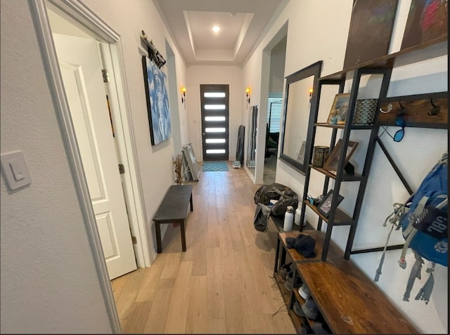 corridor with a raised ceiling and light wood-type flooring