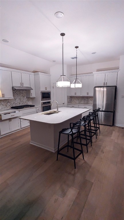 kitchen featuring appliances with stainless steel finishes, dark hardwood / wood-style floors, white cabinets, and an island with sink