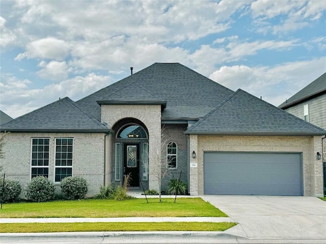 french provincial home featuring a front yard and a garage