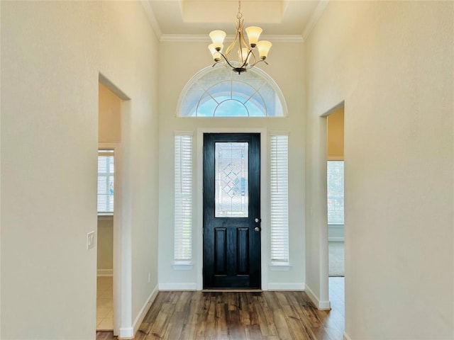 foyer entrance featuring crown molding, hardwood / wood-style floors, a healthy amount of sunlight, and an inviting chandelier