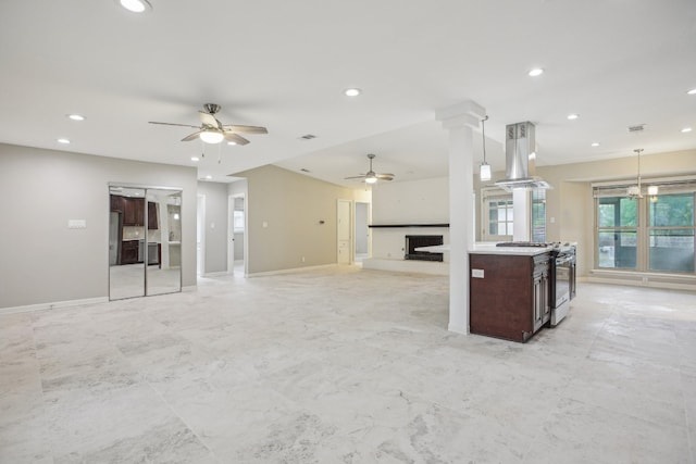 kitchen featuring decorative columns, stainless steel range, island exhaust hood, a kitchen island, and pendant lighting