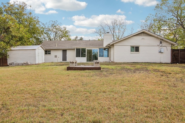 back of house with a storage unit and a yard