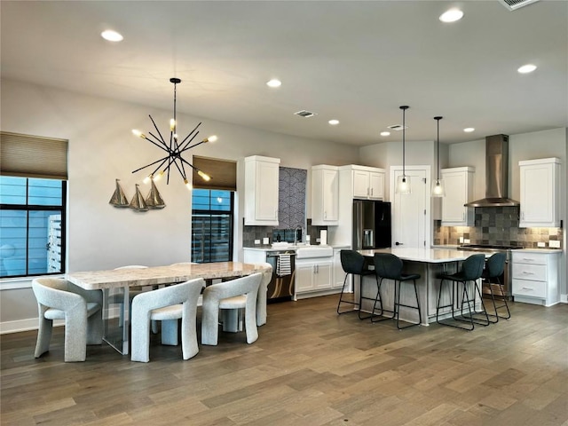 kitchen featuring white cabinetry, hanging light fixtures, a center island, and wall chimney exhaust hood