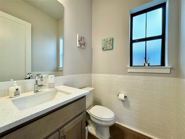 bathroom featuring vanity, tile walls, and toilet