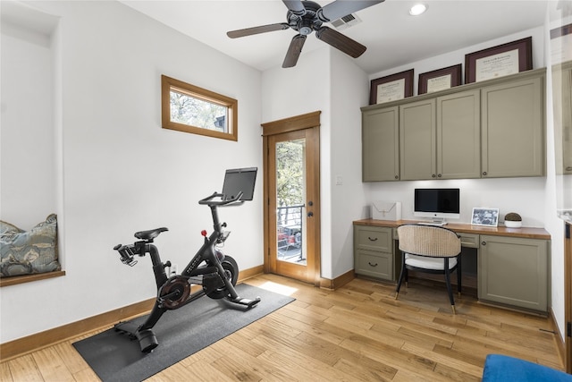 workout room with built in desk, ceiling fan, and light hardwood / wood-style flooring