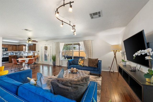 living room with ceiling fan, dark hardwood / wood-style flooring, and a textured ceiling