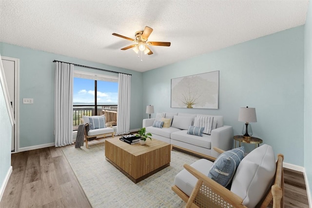 living room with a textured ceiling, light hardwood / wood-style floors, and ceiling fan