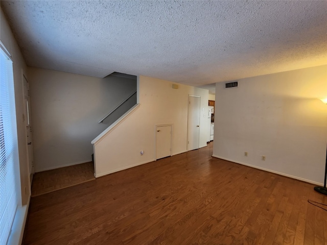 empty room with a textured ceiling and dark hardwood / wood-style floors