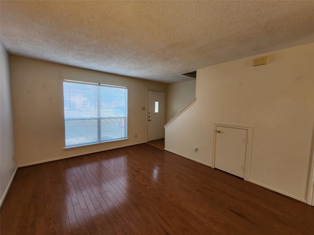 empty room featuring dark wood-type flooring and a textured ceiling