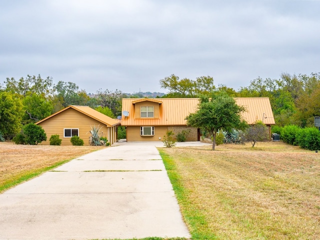 view of front of property featuring a wall mounted AC and a front lawn