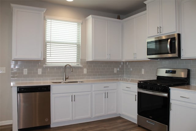 kitchen with sink, dark wood-type flooring, decorative backsplash, white cabinets, and appliances with stainless steel finishes