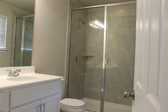 bathroom featuring vanity, toilet, and a shower with shower door