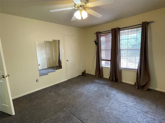 spare room with ceiling fan and dark carpet