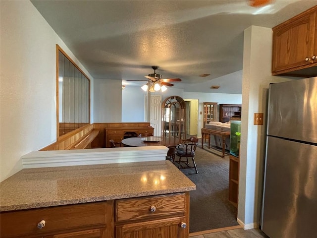 kitchen featuring ceiling fan, stainless steel fridge, a textured ceiling, and light carpet