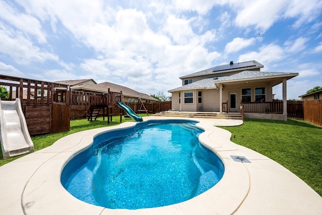 view of swimming pool featuring a water slide, a lawn, a patio area, and a playground