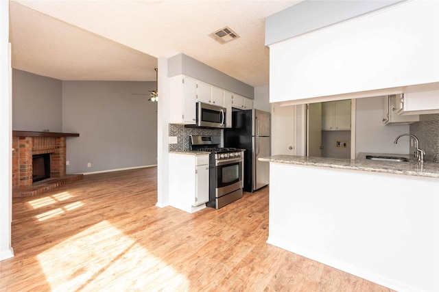 kitchen featuring stainless steel appliances, sink, white cabinets, and light stone counters