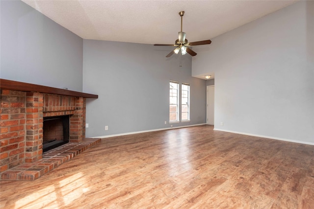 unfurnished living room featuring ceiling fan, a fireplace, hardwood / wood-style floors, and a textured ceiling