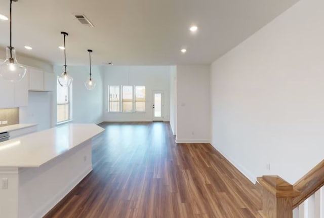 kitchen with dark wood-type flooring, white cabinets, decorative light fixtures, and a kitchen island