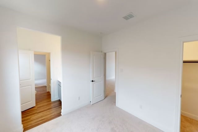 unfurnished bedroom with a closet, light wood-type flooring, and a walk in closet