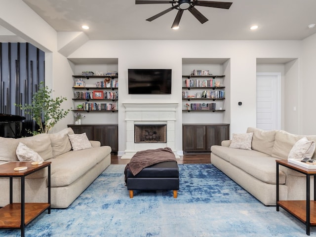 living room with built in shelves, hardwood / wood-style floors, a fireplace, and ceiling fan