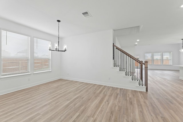 unfurnished dining area featuring light wood-type flooring and an inviting chandelier