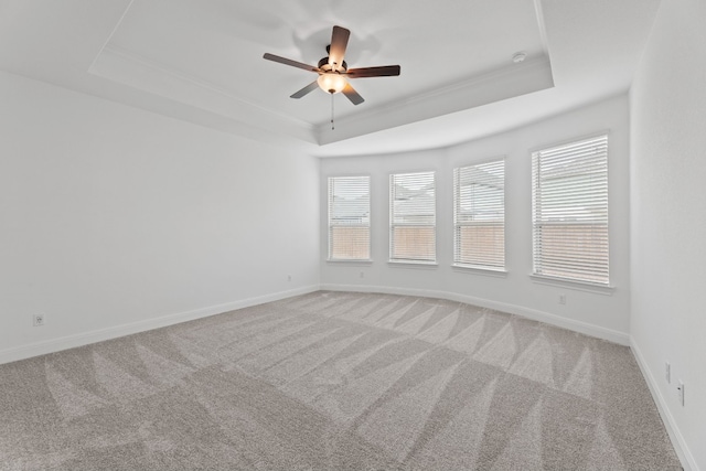 empty room featuring a tray ceiling, ceiling fan, carpet flooring, and ornamental molding