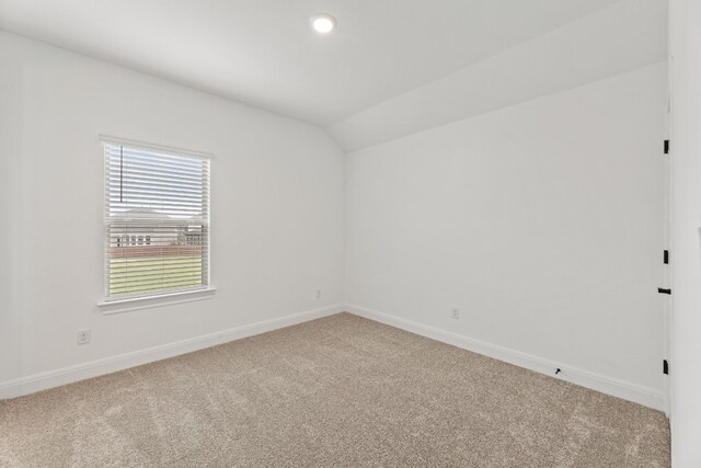 spare room with carpet flooring and lofted ceiling