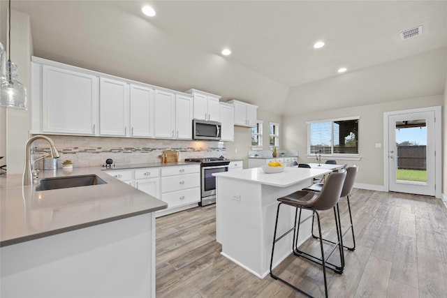 kitchen with light hardwood / wood-style floors, white cabinetry, stainless steel appliances, and sink