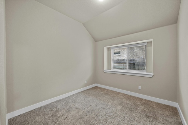 carpeted spare room featuring lofted ceiling