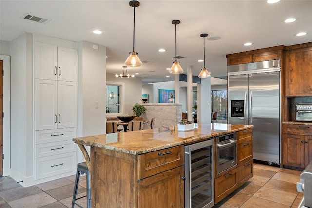 kitchen featuring appliances with stainless steel finishes, a breakfast bar area, beverage cooler, a center island, and white cabinets