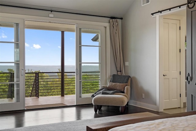bedroom featuring baseboards, visible vents, a barn door, and wood finished floors