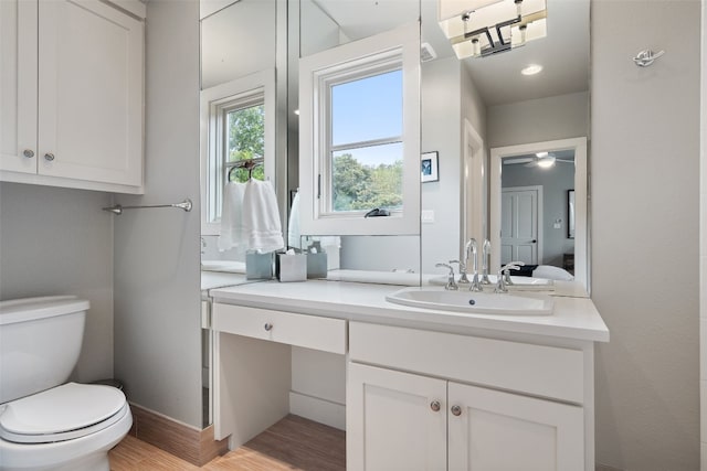 bathroom featuring vanity, hardwood / wood-style flooring, toilet, and ceiling fan