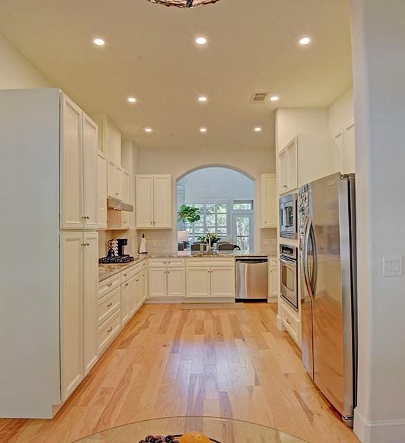 7800 SW Pkwy Unit 510, Austin, TX 78735 - kitchen with stainless steel appliances, arched walkways, light wood-style floors, recessed lighting, and white cabinetry