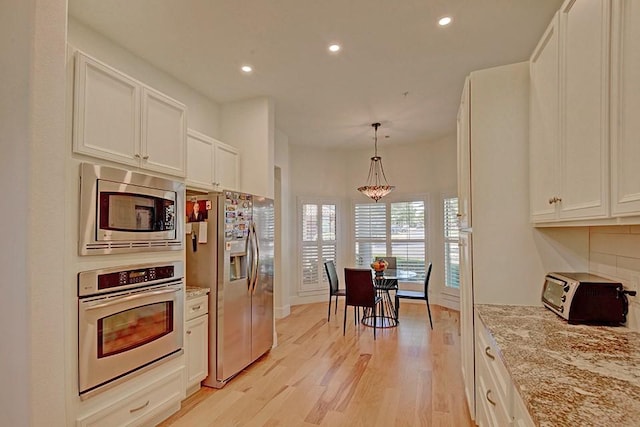 7800 SW Pkwy Unit 510, Austin, TX 78735 - kitchen with stainless steel appliances, light wood-style floors, recessed lighting, tasteful backsplash, and white cabinets