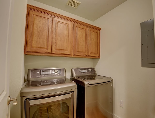 laundry area with electric panel, cabinets, and washer and dryer