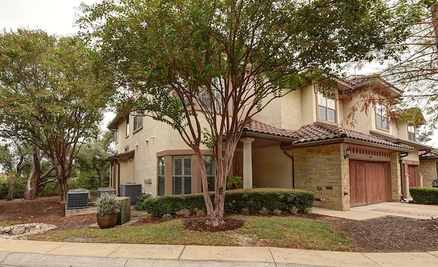 7800 SW Pkwy Unit 510, Austin, TX 78735 - view of front facade with central AC unit, an attached garage, stone siding, and stucco siding
