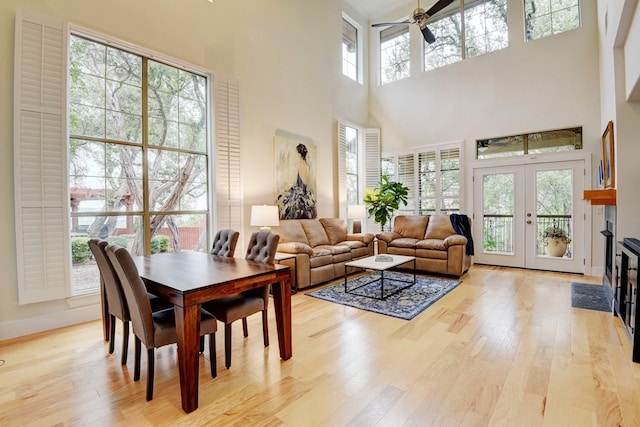 dining room featuring ceiling fan, light hardwood / wood-style floors, a high ceiling, and french doors