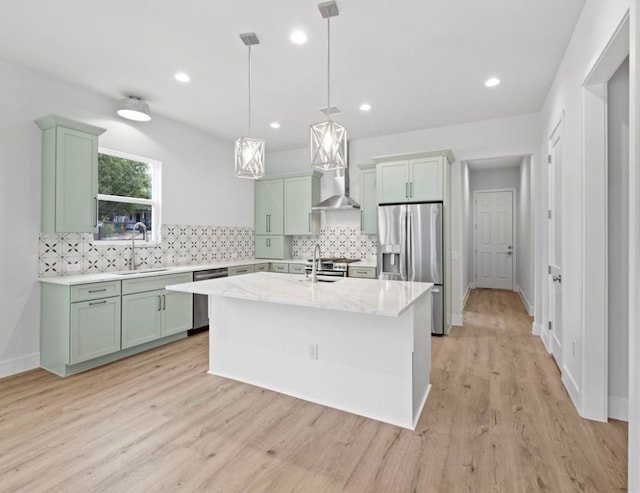 kitchen featuring a kitchen island with sink, light hardwood / wood-style flooring, stainless steel appliances, sink, and light stone countertops