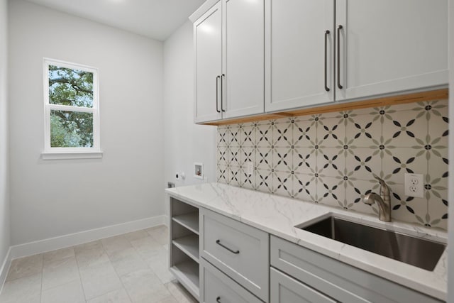 kitchen with sink, decorative backsplash, white cabinets, and light stone counters