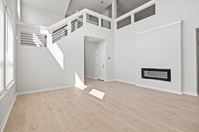 unfurnished living room featuring light wood-type flooring and high vaulted ceiling