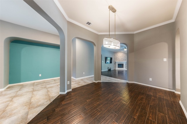 empty room with crown molding, wood-type flooring, and a fireplace