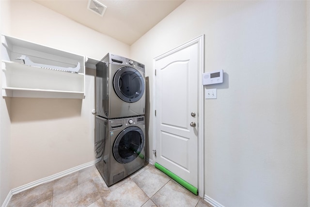 laundry area featuring stacked washing maching and dryer and light tile patterned floors