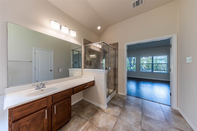 bathroom featuring a shower with door, lofted ceiling, vanity, and tile patterned flooring