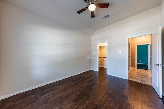 unfurnished bedroom featuring lofted ceiling, ceiling fan, a spacious closet, dark hardwood / wood-style floors, and a closet