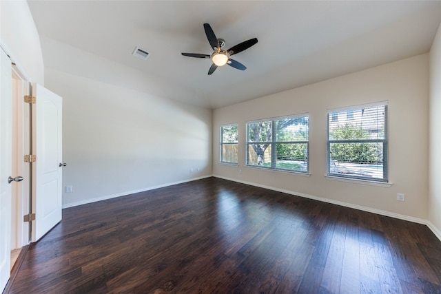 empty room with a wealth of natural light, dark hardwood / wood-style floors, and ceiling fan