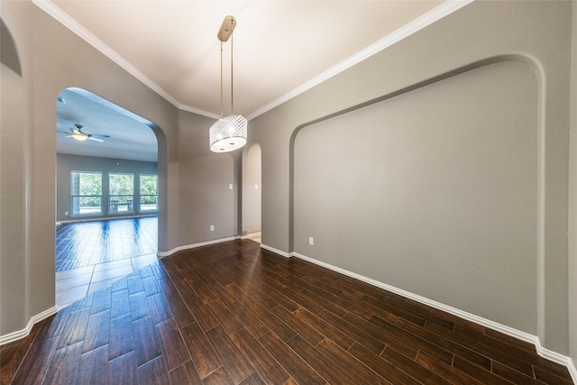 empty room with ornamental molding, dark wood-type flooring, and ceiling fan