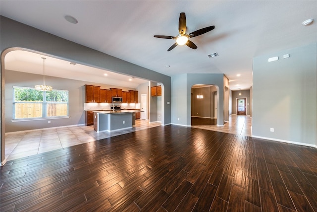 unfurnished living room with wood-type flooring and ceiling fan with notable chandelier